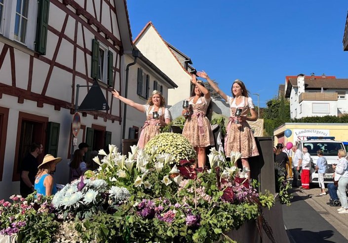 Drei junge Damen winken, stehend auf einem Festumzugswagen