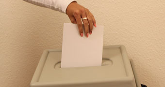 Stimmzettel wird in eine Urne eingeworfen